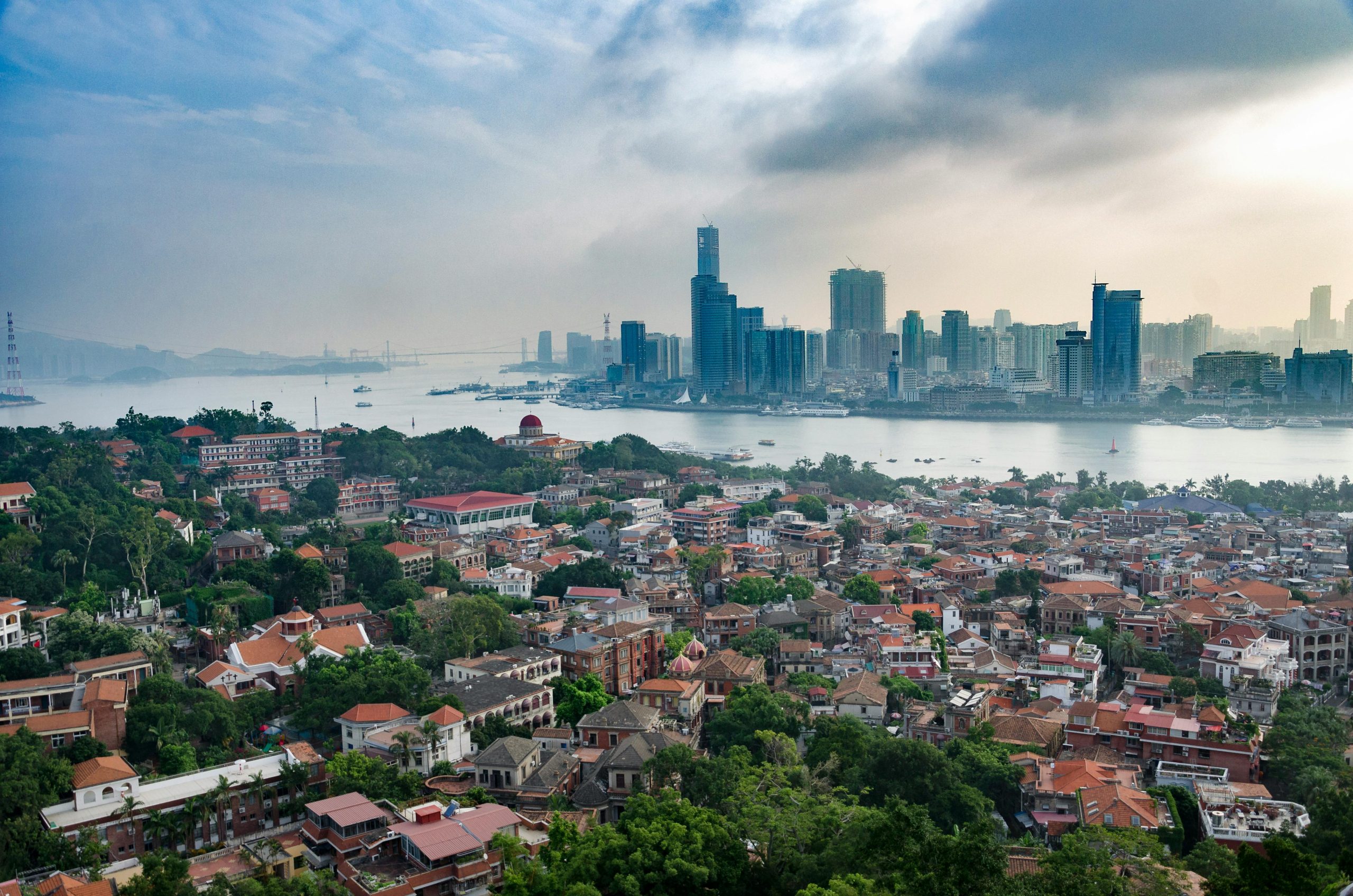 Scenic aerial view of Xiamen city skyscrapers and residential districts with lush greenery and waterways.