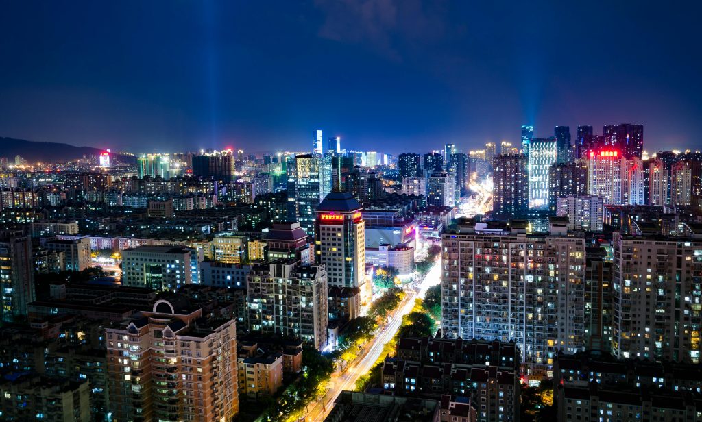 A vibrant night view of Fuzhou cityscape, featuring illuminated buildings and bustling streets.