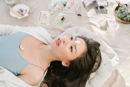 Asian woman meditating with gemstones and tarot cards, promoting relaxation and wellbeing.