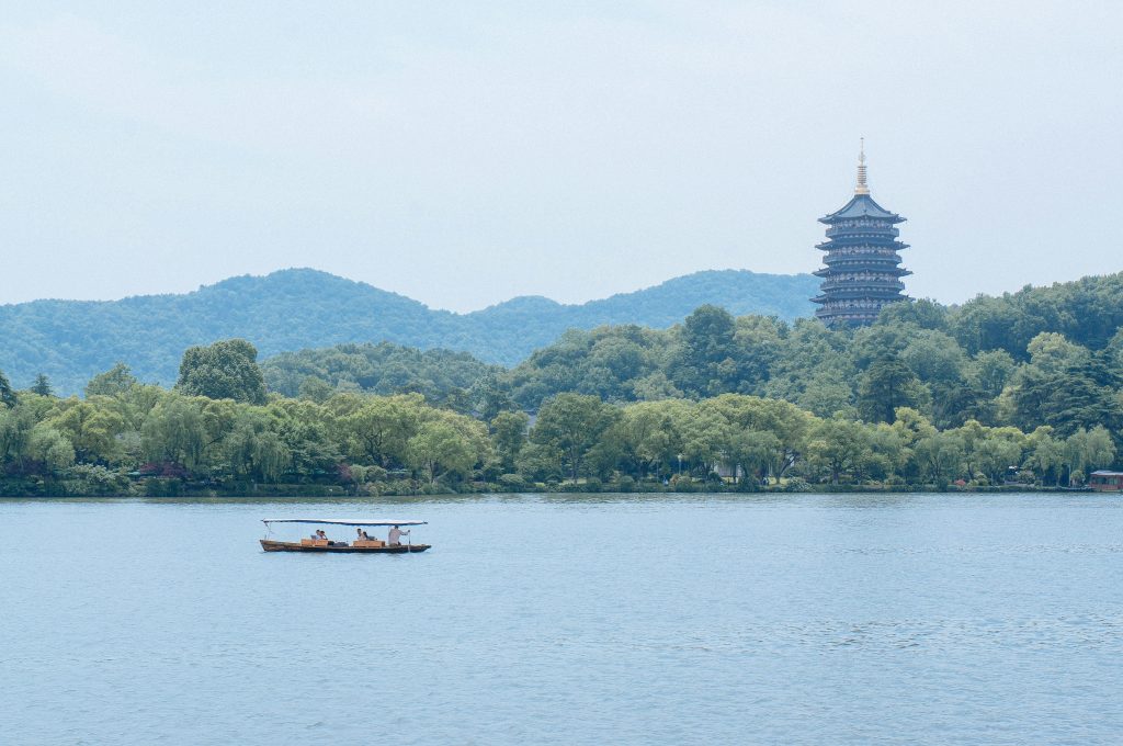 Peaceful scene featuring a boat on West Lake with Leifeng Pagoda in Hangzhou, China.